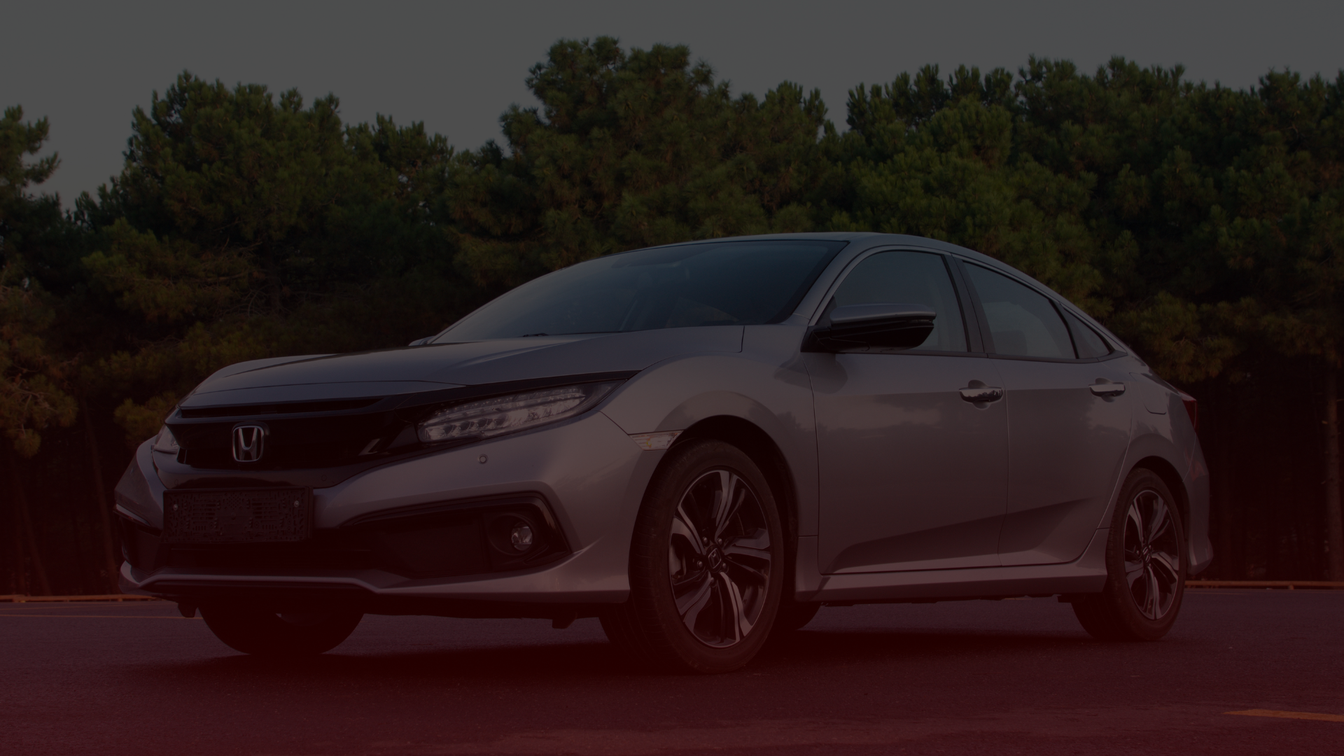 A sleek silver sedan, possibly serviced by a trusted Honda mechanic in Greater Toronto, sits parked on a paved road. It boasts dark-tinted windows against a backdrop of dense green trees under an overcast sky. EuroMechanic | Top Reviewed Auto Repair Shop | Greater Toronto and Guelph | Visit Euromechanic