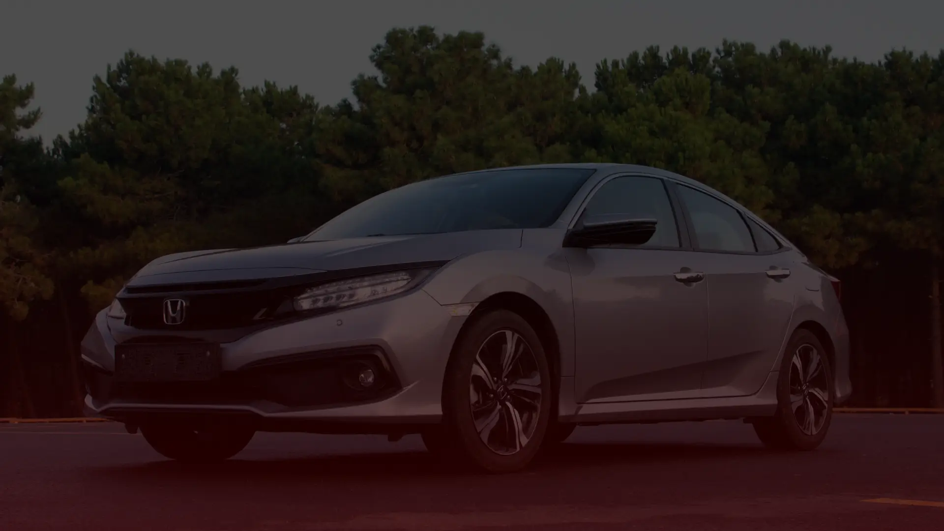 A sleek silver sedan, possibly serviced by a trusted Honda mechanic in Greater Toronto, sits parked on a paved road. It boasts dark-tinted windows against a backdrop of dense green trees under an overcast sky. EuroMechanic | Top Reviewed Auto Repair Shop | Greater Toronto and Guelph | Visit Euromechanic