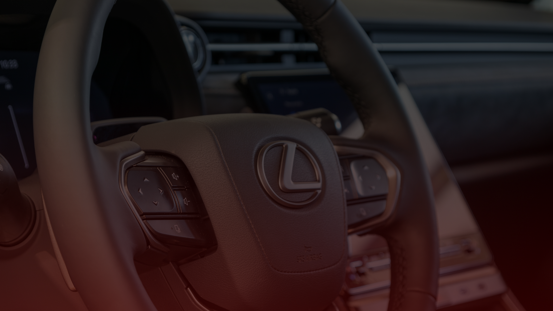 Close-up view of a Lexus steering wheel, with the brands logo at the center. The interior boasts black leather and visible control buttons, hinting at precision akin to an Acura mechanics craftsmanship in Greater Toronto and Guelph, with a dashboard glimpse in the background. EuroMechanic | Top Reviewed Auto Repair Shop | Greater Toronto and Guelph | Visit Euromechanic