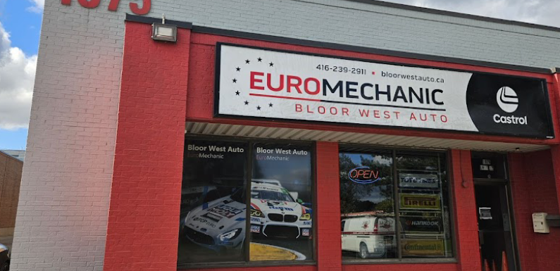 Storefront of Euro Mechanic Bloor West Auto. Features a red and white sign with contact details and logos. The window displays racing car images and an Open sign. Located at 1075, this welcoming location prominently showcases the Castrol logo. EuroMechanic | Top Reviewed Auto Repair Shop | Greater Toronto and Guelph | Visit Euromechanic